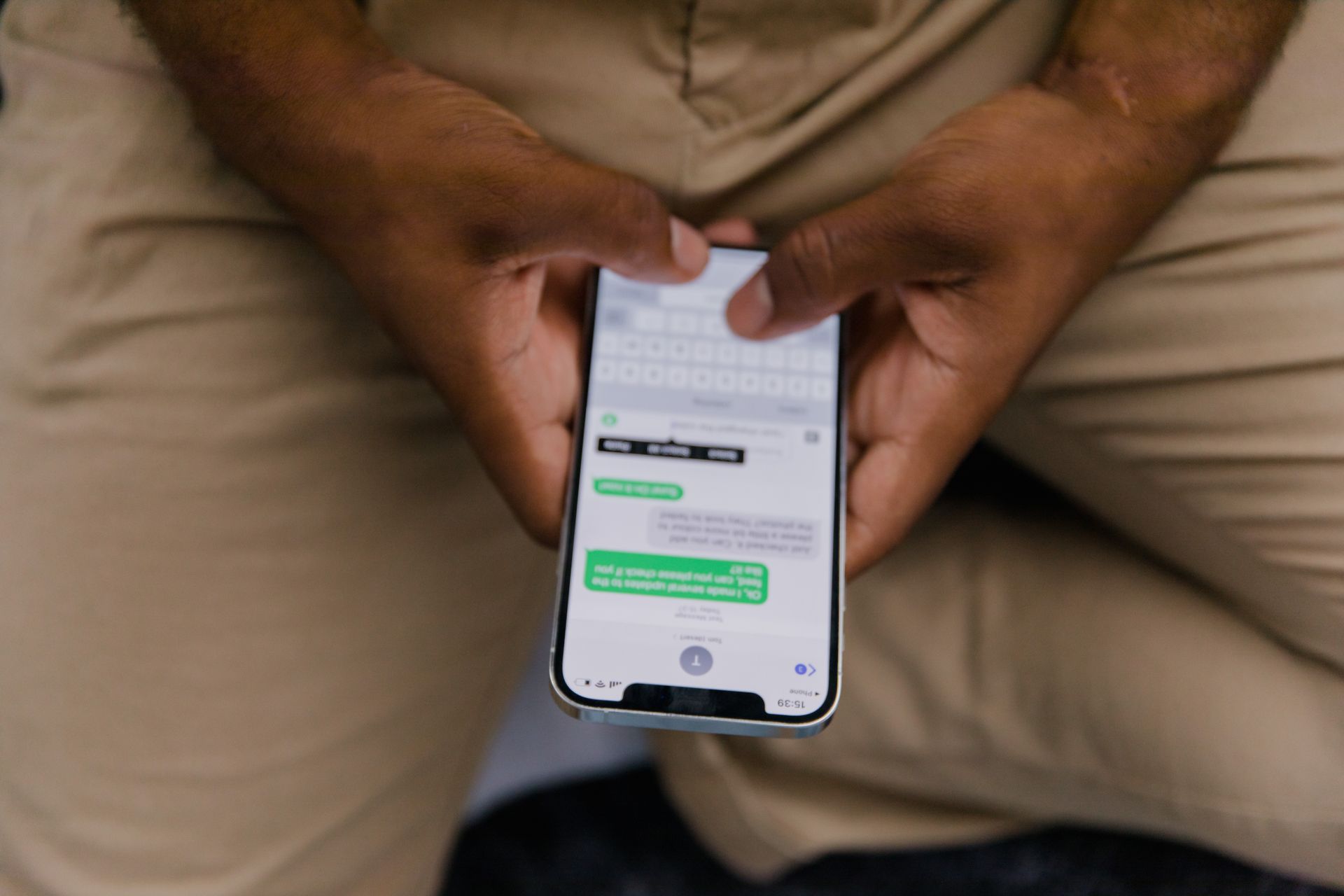 Mãos segurando um smartphone com uma conversa de mensagens na tela